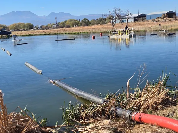 Hydraulic dredge and floating pipeline on a settling pond
