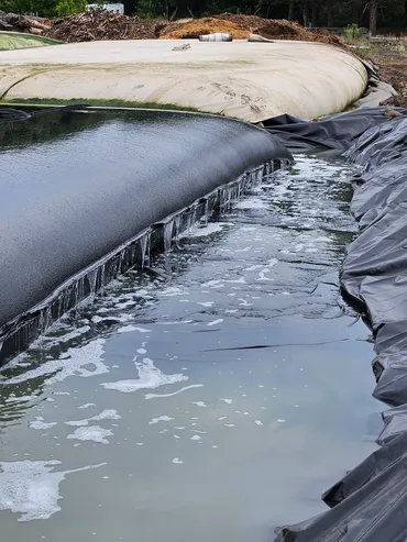 Geotextile dewatering tube beside a lined lagoon