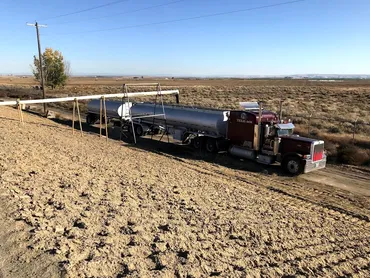 Tanker truck delivering material to an agricultural field